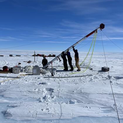 Researchers lift an ice core driller in Allan Hills, Antarctica