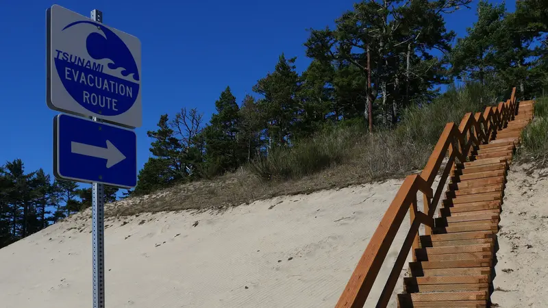 A tsunami evacuation sign points up a staircase toward higher ground.
