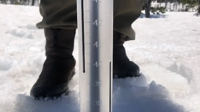Student sticking a metal coring tube into snow