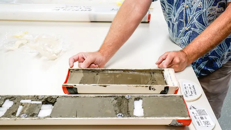 Close up of person examining sediment core on a table