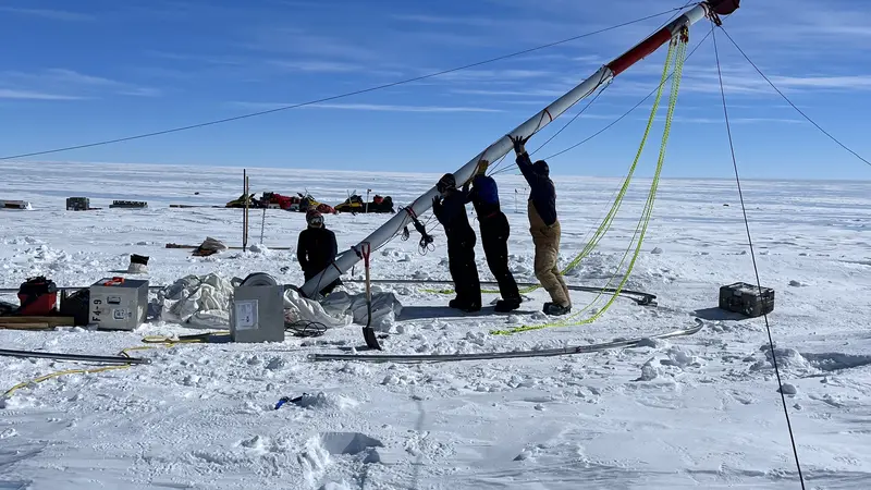 Researchers lift an ice core driller in Allan Hills, Antarctica