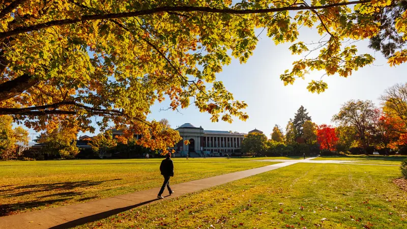 Person walking on a sidewalk on the quad in front of the Memorial Union at Oregon State University.