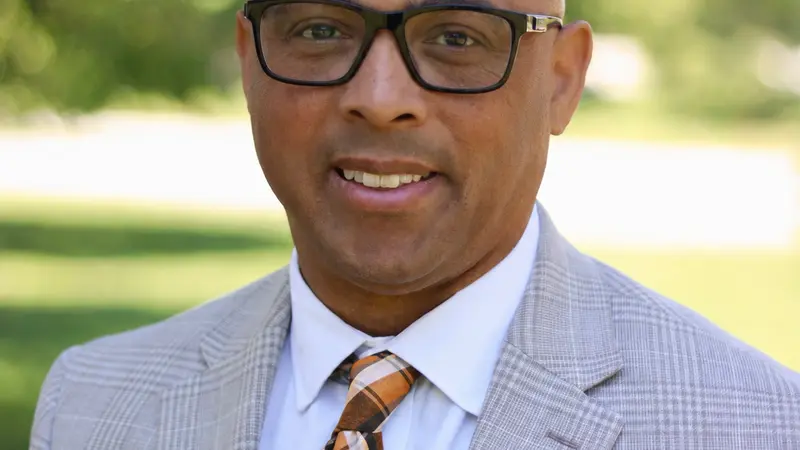 Man wearing glasses smiles at the camera.