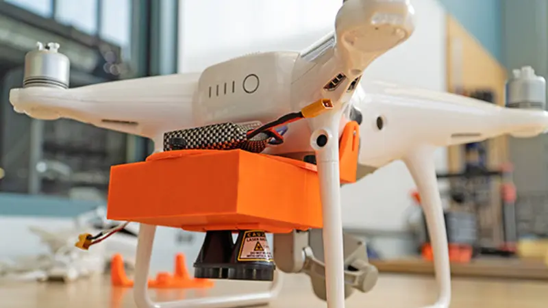 Image of white and orange drone on a countertop. 
