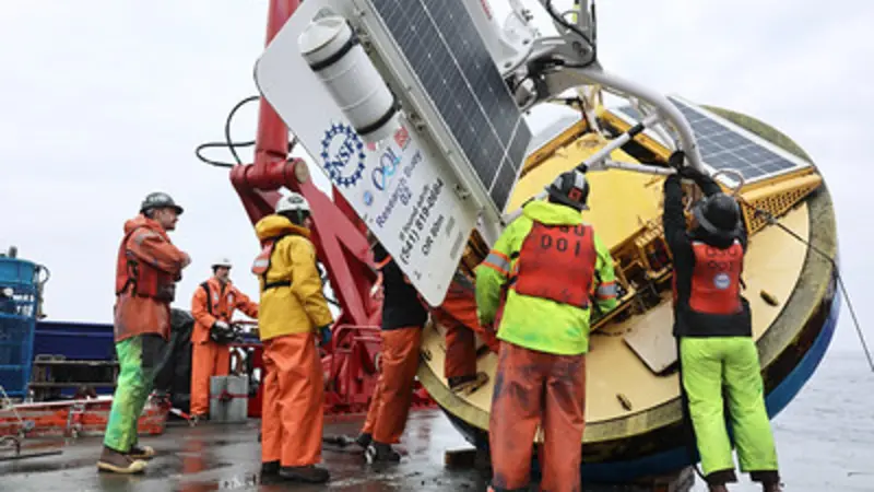 Image of a crew working on a large research buoy aboard a research vessel. 
