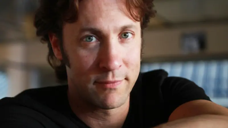 Headshot of David Eagleman, who looks straight at the camera over his arms folded in front of him