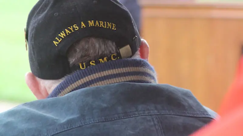 An image from a Veterans Day ceremony at OSU shows an older man wearing a baseball cap that says "Always a Marine."