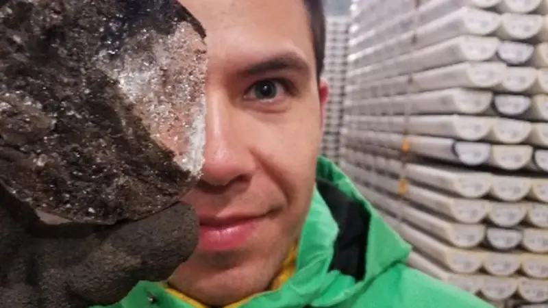 Adrian Gallo holds a disc of ice from a permafrost core in the OSU corelab freezer.