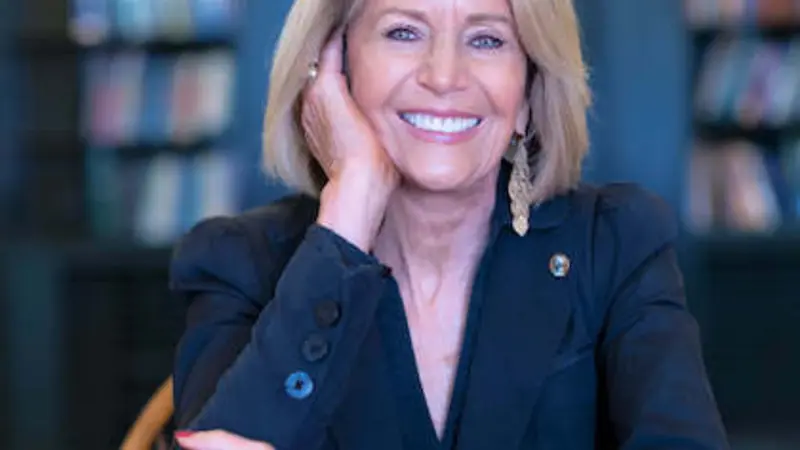 Headshot of Marcia McNutt, president of the National Academy of Sciences. She has short blonde hair and is wearing a dark blue blazer, seated with her elbows propped on a table and one hand supporting her chin as she looks at the camera.