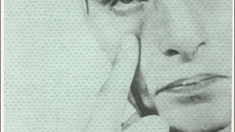 Image is one of a series of 9 panels in a Barbara Kruger artwork; image is a black & white headshot of a man with short dark hair and a frown, with his index finger placed under his right eye. Red letters spelling "SEEN" are placed one in each corner