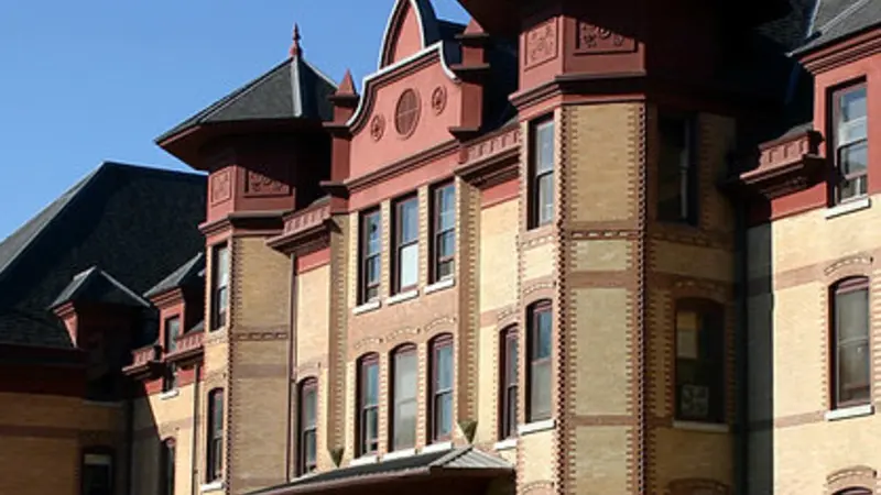 Stock image of Waldo Hall, red and yellow brick building with black roof and arched entry