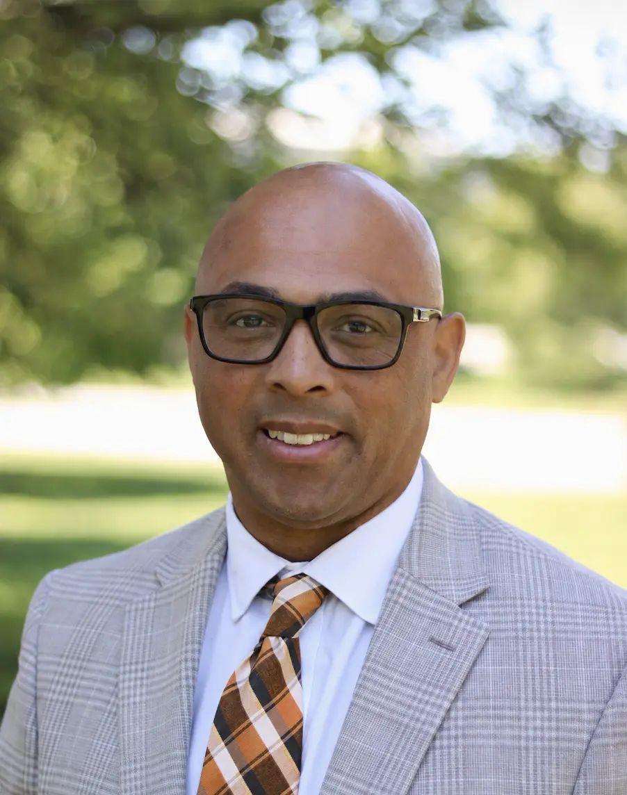 Man wearing glasses smilles at the camera.