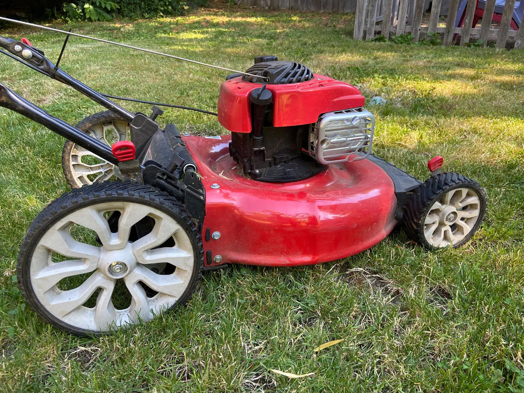 A red lawn mower sitting on fresh cut green grass.