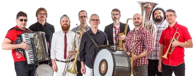 The 9 members of Slavic Soul Party! stand with their instruments
