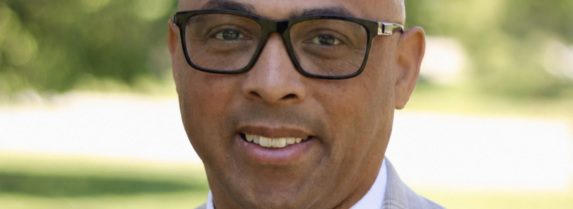 Man wearing glasses smilles at the camera.