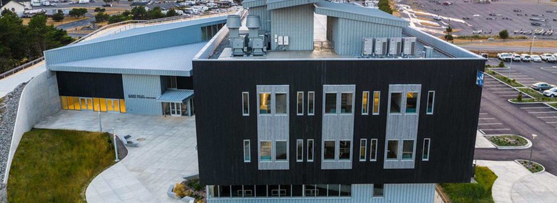 Image of an aerial view of the Gladys Valley Marine Studies Building with the Yaquina Bay Bridge in the background. 