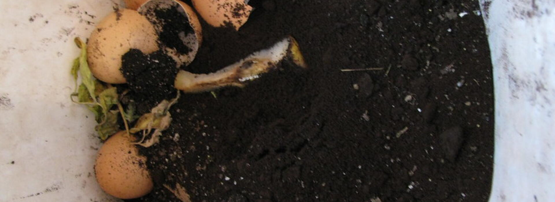 coffee grounds are mixed into a compost container with egg shells