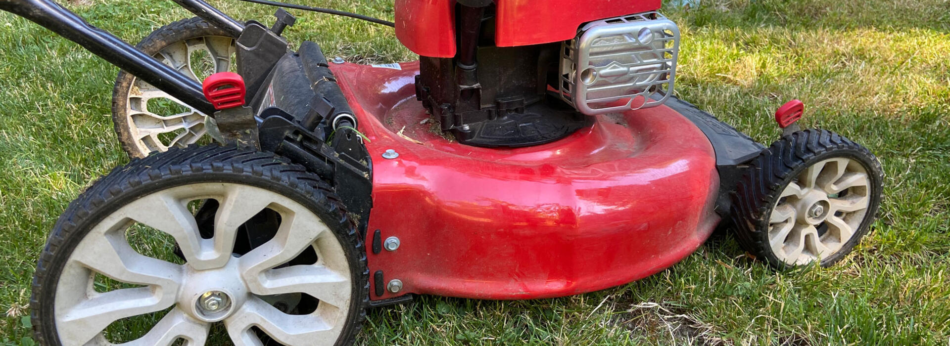 A red lawn mower sitting on fresh cut green grass.