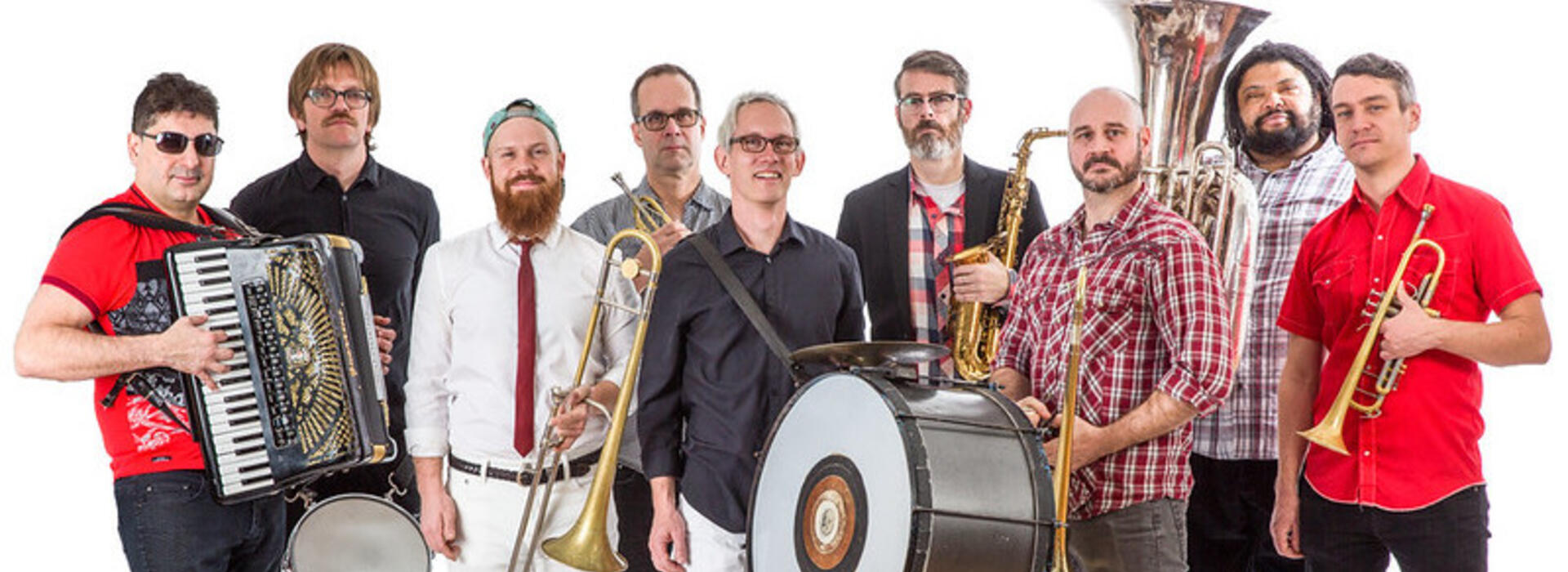 The 9 members of Slavic Soul Party! stand with their instruments