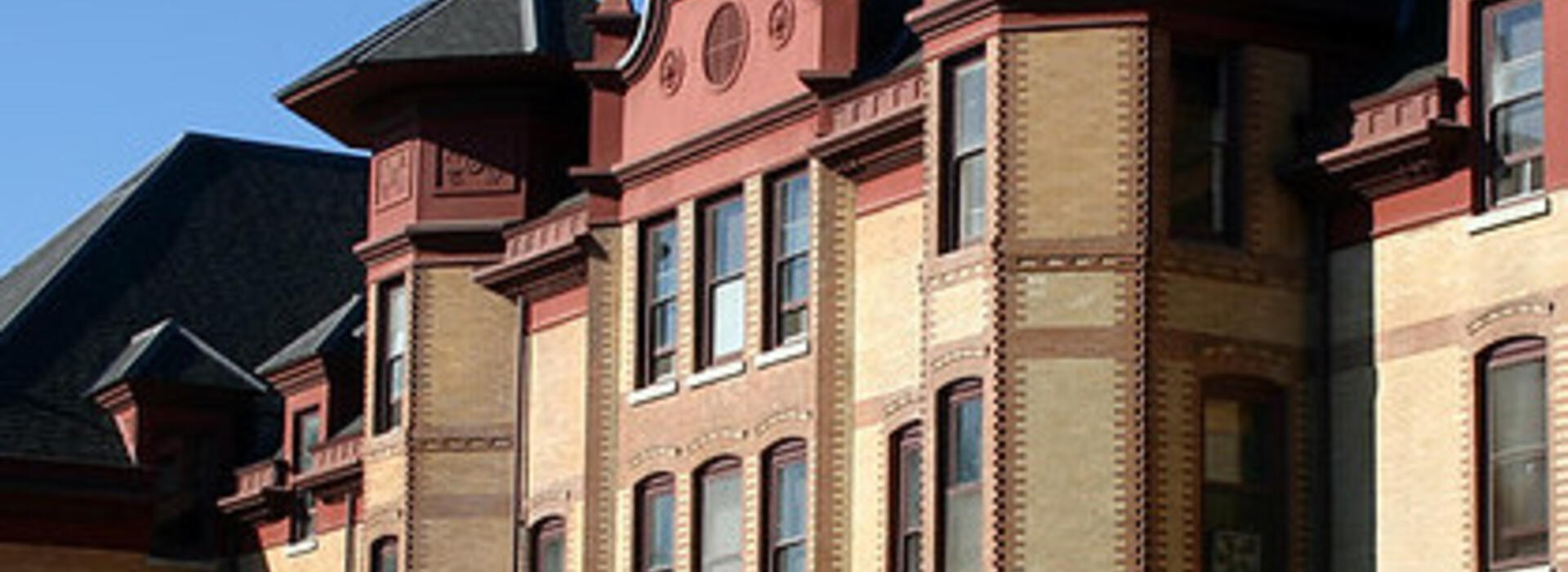 Stock image of Waldo Hall; building is old-fashioned yellow brick with red at the top and black roofs on the spires.