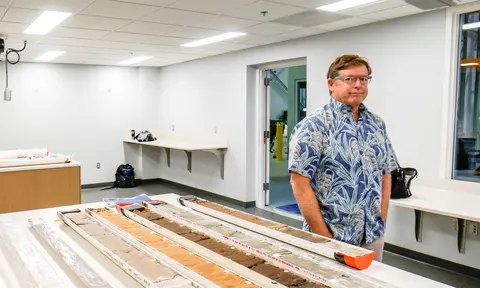 Chris Goldfinger standing next to table with sediment cores on top