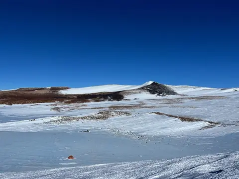 Snow-covered rocky hillside against a bright blue cloudless sky.