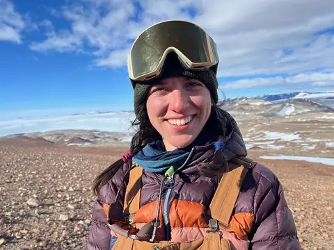 Julie Marks-Peterson wearing cold weather gear, standing on a gravel and snow covered landscape. 