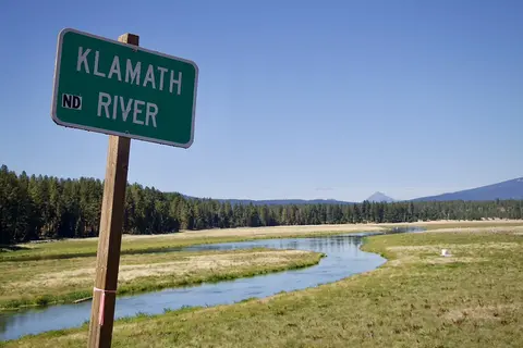 Sign saying Klamath River next to the river with trees in background